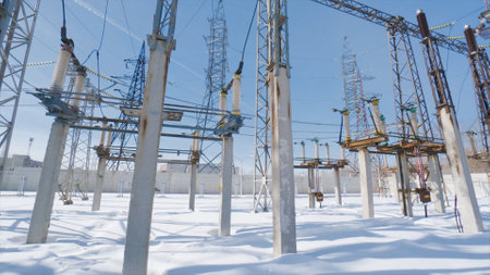 Poles and cables of power plant in winter. Action. Power plant in field on sunny winter day....