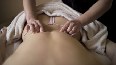 Close up process of relaxing back massage. Action. Woman having calming and antistress procedure at spa center performed by a professional masseur.の写真素材