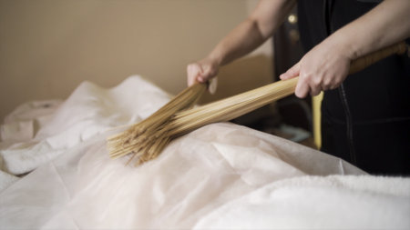 Female masseuse working with woman and performing Japanese massage with bamboo sticks in a spa salon. Action. People, beauty, healthy lifestyle and relaxation concept.の写真素材