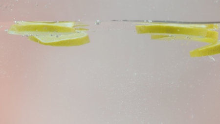 Close up of falling lemon slices into splashing water. Action. Fresh citrus fruit slices falling down into fresh vitamin beverage.の写真素材