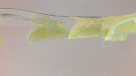 The freshness of lemon slices in clear water, closeup. Action. Citrus natural drink with a lot of vitamin c, concept of healthy and fresh beverages.の写真素材