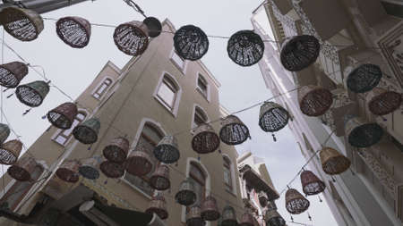 Bottom view of beautiful wicker baskets with nazar amulets hanging in the city streets between...