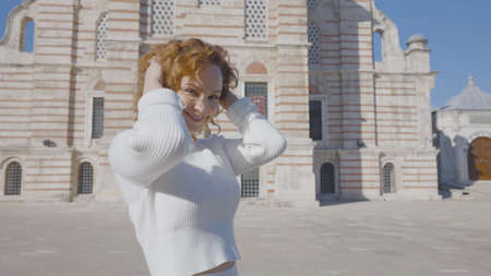 Beautiful woman walks to cathedral in sunny day. Action. Attractive woman walks happily to bright...