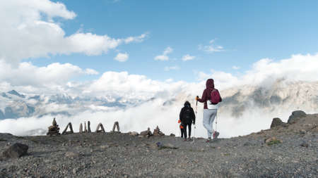 Rear view of travelers climbing a mountain slope with sticks for tracking. Clip. Extreme sport and...
