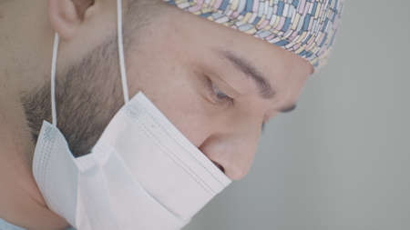 Close-up of masked surgeon during surgery. Action. Young professional surgeon in mask looks down. Surgeon is concentrating on performing operation. Beautiful surgeon on internshipの写真素材