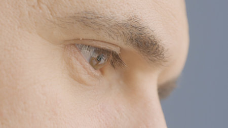 Close-up of mans eyes while working. Action. Look of man at work on laptop. Man watches typing on keyboard and laptop monitorの写真素材