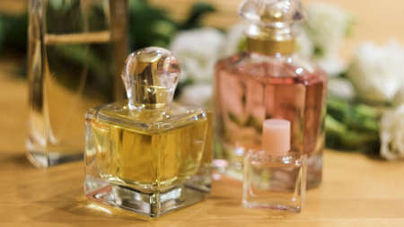 Close up of woman hand putting small glass bottle of perfume on a table. Concept. Bottles of...