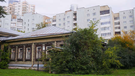 Rustic house on background of urban buildings. Stock footage. Contrast in architecture of old town. Old wooden house on background of residential high-rise buildingsの写真素材