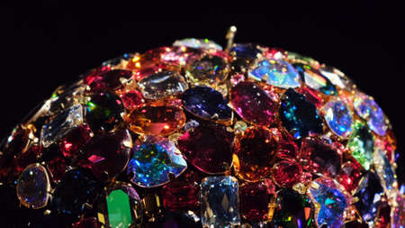 Close up of rotating jewelry made of many shining crystals or gems isolated on black background....