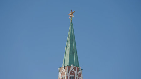 Nikolskaya tower of Moscow kremlin. Action. Bottom view of historic red brick tower on background of blue sky. Beautiful tower on Red Square in Russiaの写真素材