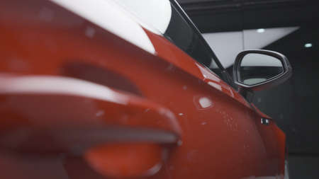 Close up of clean, shiny, new car stands in the parking lot of the shopping center. Action. Beautiful luxury red car side door in the garage.の写真素材