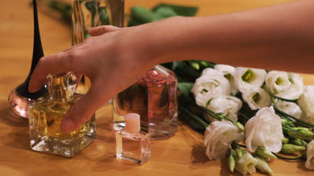 Small bottles with perfume and flowers on a wooden table. Concept. Close up of woman choosing a...