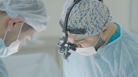 Surgeons are concentrating on operation. Action. Two surgeons are concentrating on operating on patient under anesthesiaの写真素材