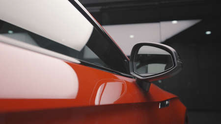 Close up of clean, shiny, new car stands in the parking lot of the shopping center. Action. Beautiful luxury red car side door in the garage.の写真素材