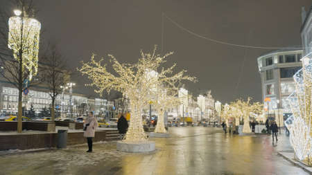 Russia, Moscow - December, 2020: Beautiful decorated city before Christmas. Action. Bright Christmas decorations with garlands in busy city. Decorations, installations and arches with shining garlands on background of gray city.の写真素材