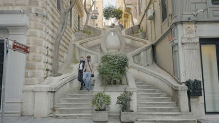 ISTANBUL, TURKEY - MARCH, 2021: Ornate staircase on street. Action. Couple descends beautiful curved staircase in alley. Beautiful staircase in ancient alley of southern cityのeditorial素材