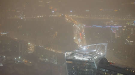 Top view of city at night in cloudy weather. Action. Night city in lights is moving lively in cloudy...