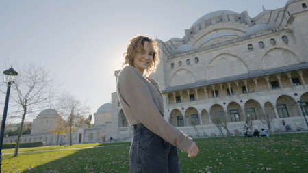 Beautiful woman posing on background of temple. Action. Happy woman dances outside mosque on sunny day. Beautiful woman circling near mosque on background of sun raysの写真素材