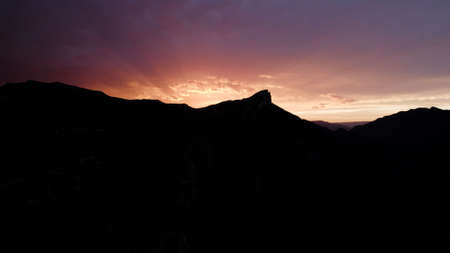 Aerial view of mountain range in front of stunning sunrise. Action. Colorful sky contrasting with black rock silhouette.の写真素材
