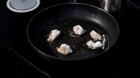 Homemade sauteed chicken breast in a frying pan. Art. Close up of turning chopped chicken breast in flour at the kitchen.の写真素材