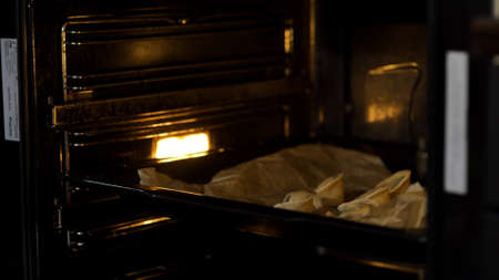 Close up of putting dumplings inside the oven. Art. Baking dumplings on a tray, concept of cooking food at home.の写真素材