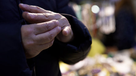 Close up of an old woman trying to put on a ring on her finger. Art. Elderly female in a warm coat trying on a ring.の写真素材