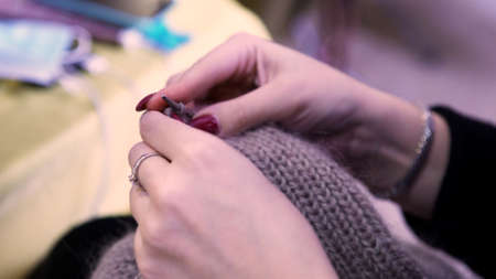 The designer of clothes manually knitting a brown sweater. Art. Close up of a young woman hands...