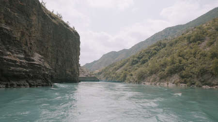 Breathtaking view of a turquoise flowing river between green mountains. Action. Concept of...