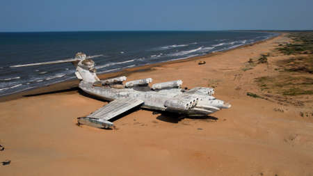 Aerial view of a ruined abandoned airplane found in an uninhabited island near the sea on blue sky...