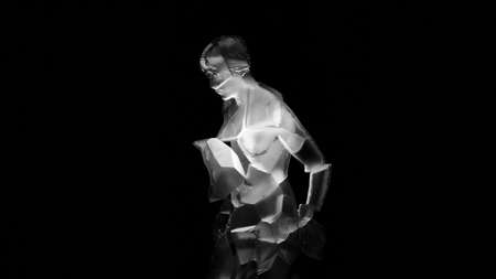 Statuette of man. Design. Glowing figure of man on black background. Glass geometric figure of man with light. Statuette of man rotates and glows on black backgroundの写真素材