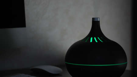 Workplace humidifier. Action. Modern luminous humidifier on desktop. Air freshener with aromatic oils creates atmosphere and comfortable working environmentの写真素材
