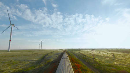 Top view of freight train on green field background. Shot. Drone follows train at speed. Train rides...