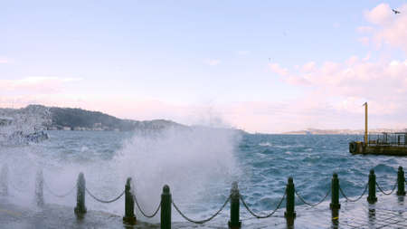 Beautiful view of marina with splash of waves. Action. City marina with big waves in windy weather. Waves come out of city pier in windy weatherの写真素材
