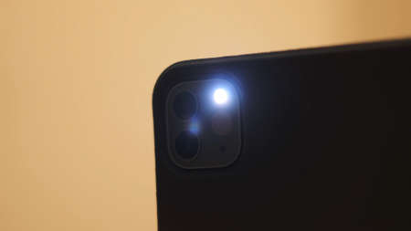 Close up of a smartphone taking a picture with a flash isolated on yellow background. Concept....