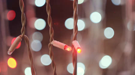 LED Christmas garlands blinking on the background of bokeh blurred lights. Concept. Close up of flashing lights of light pink color, New Year and Christmas time.の写真素材