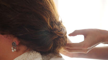 Close up of professional hairdresser hands doing beauty hairstyle for a bride. Stock footage. Preparation of a bride hair for a wedding day.の写真素材