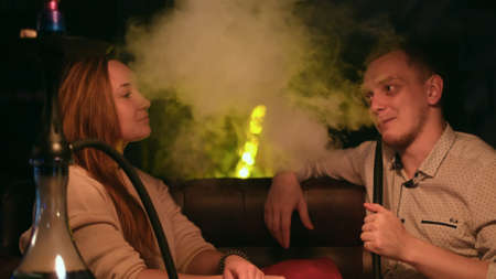 Lovely man and woman in relationship sitting together at the cafe and smoking hookah. Media. Man...
