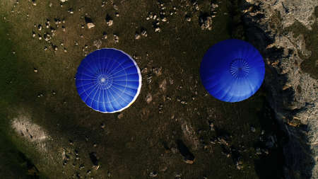 Aerial view of two blue hot air balloons flying above rural roads and green trees and fields. Shot. Flying in the sky above green nature.の写真素材