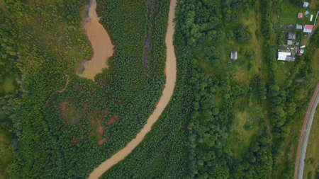 A huge dirty river in the forest. The view from the drone. Clip. A huge curving dirty river with...