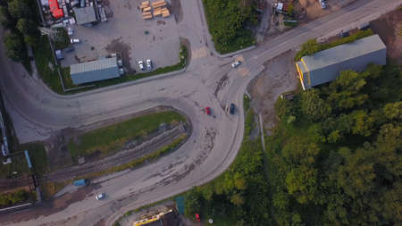 View from a helicopter . Clip. View of a curving road with cars next to a green park and some kind...
