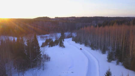 The view from the drone. Clip. A huge snowy winter forest with snowdrifts on which electric machines with a person are walking.の写真素材
