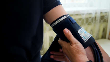 Health check . Clip. A man s blood pressure is measured using a pressure gauge .