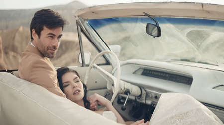 Beautiful couple in convertible. Action. Stylish newlyweds pose in convertible. Beautiful couple in...