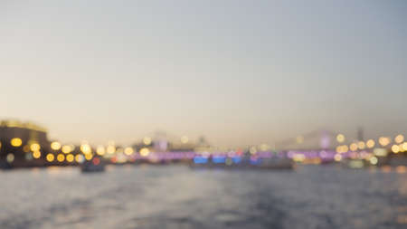 Blurred beautiful sunset landscape with bridge and lights. Action. Bokeh lantern lights decorating the bridge across the rippling river.の写真素材
