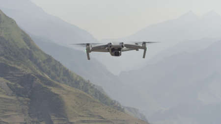Flying drone in air. Action. Drone flies over beautiful mountain landscape on sunny day. Drone in...