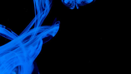 Blue ink drops underwater on a black background. Stock footage. Close up of beautiful blue paint...