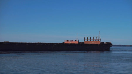 Cargo ship sailing on river on clear day. Clip. Merchant ship or barge sails along river. Commercial and industrial shippingの写真素材