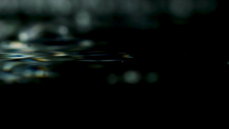 Close-up of water ripples on black background. Stock footage. Surface of clear water ripples on isolated backgroundの写真素材