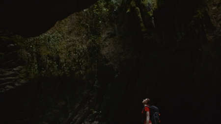 Woman at rocky cave in jungle. Creative. Hiking in rocky landscapes of wild jungle. Beautiful...