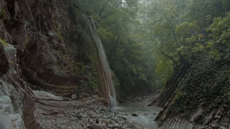 Beautiful waterfall on rock in jungle. Creative. High narrow waterfall falls from cliff in jungle....